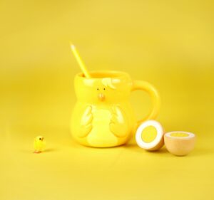 Bright yellow still life with a chick-inspired mug and decorative egg. Perfect for Easter settings.
